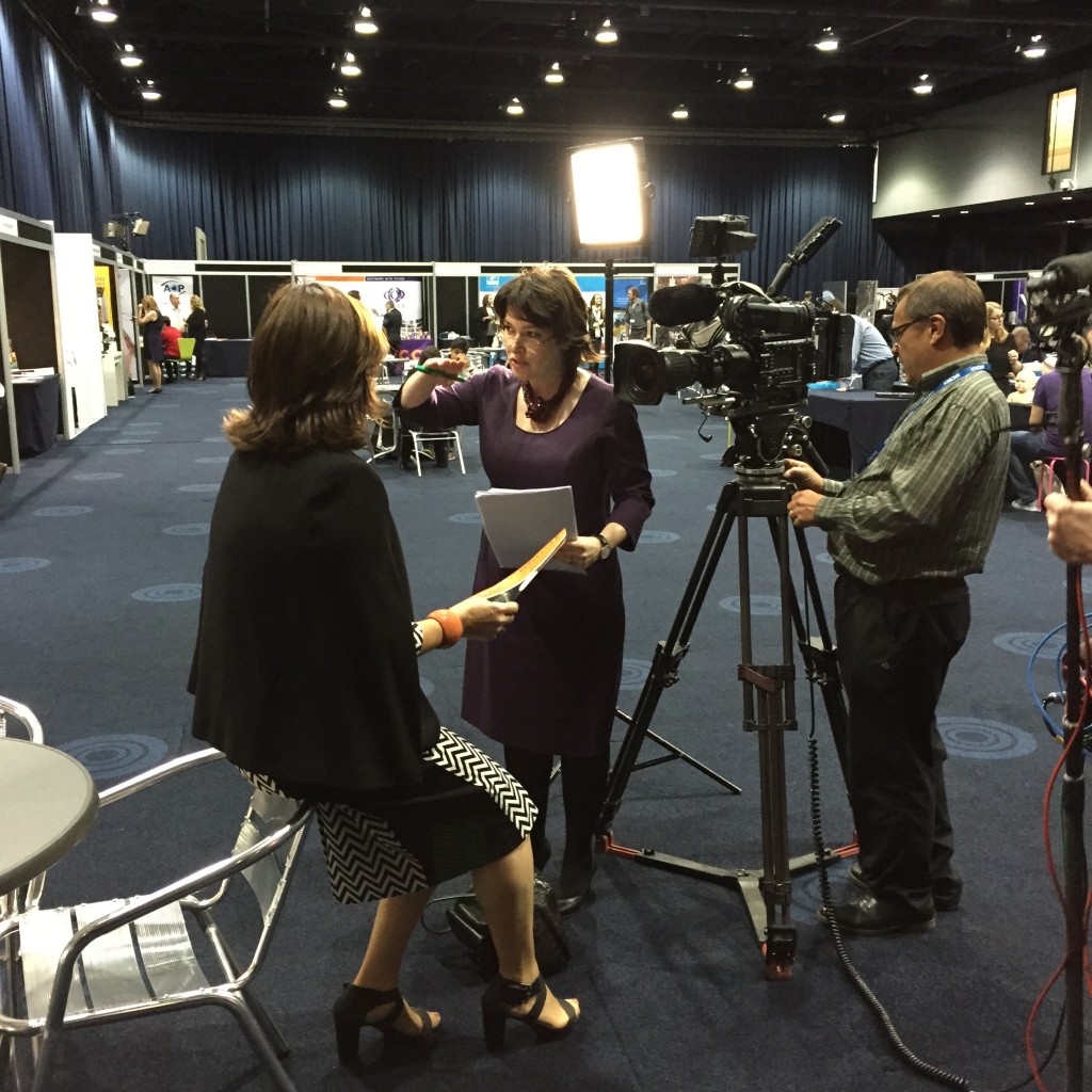 Sarah Lockett with camera crew filming at a conference 